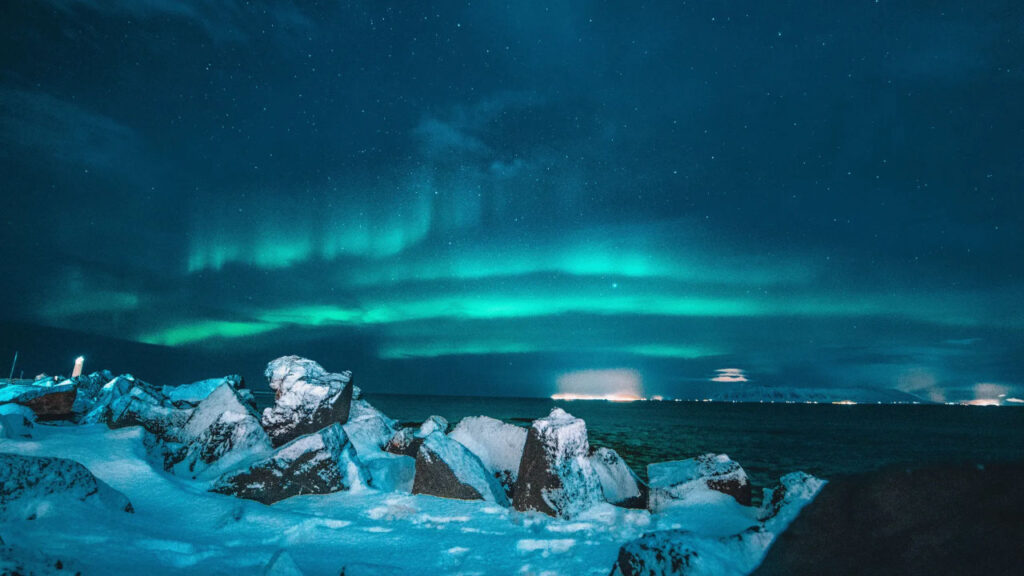 Northern lights shining over snowy rocks
